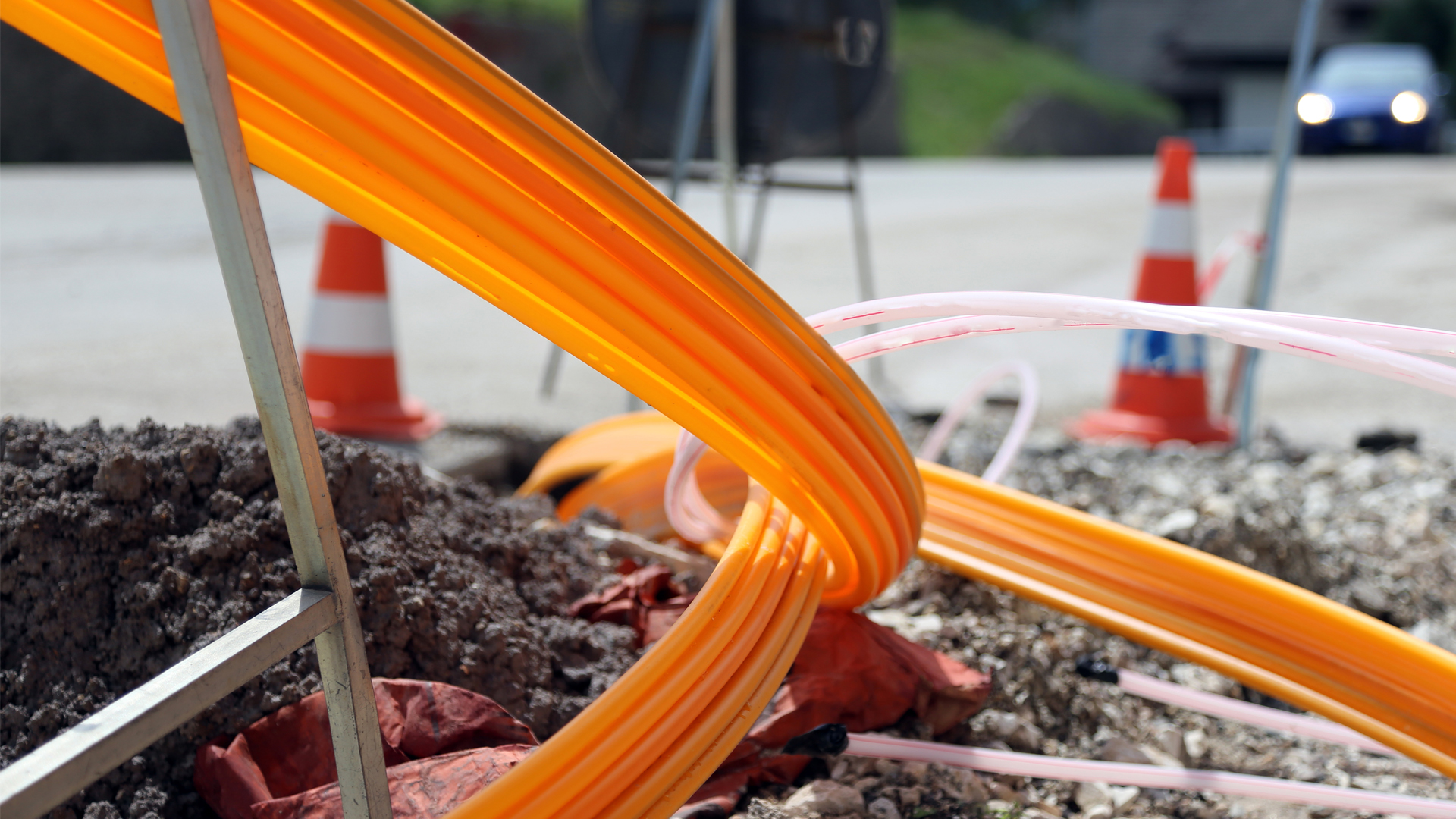 Nahaufnahme von leuchtend orangen Leerrohren für Glasfaserkabel auf einer Baustelle für den Breitbandausbau.