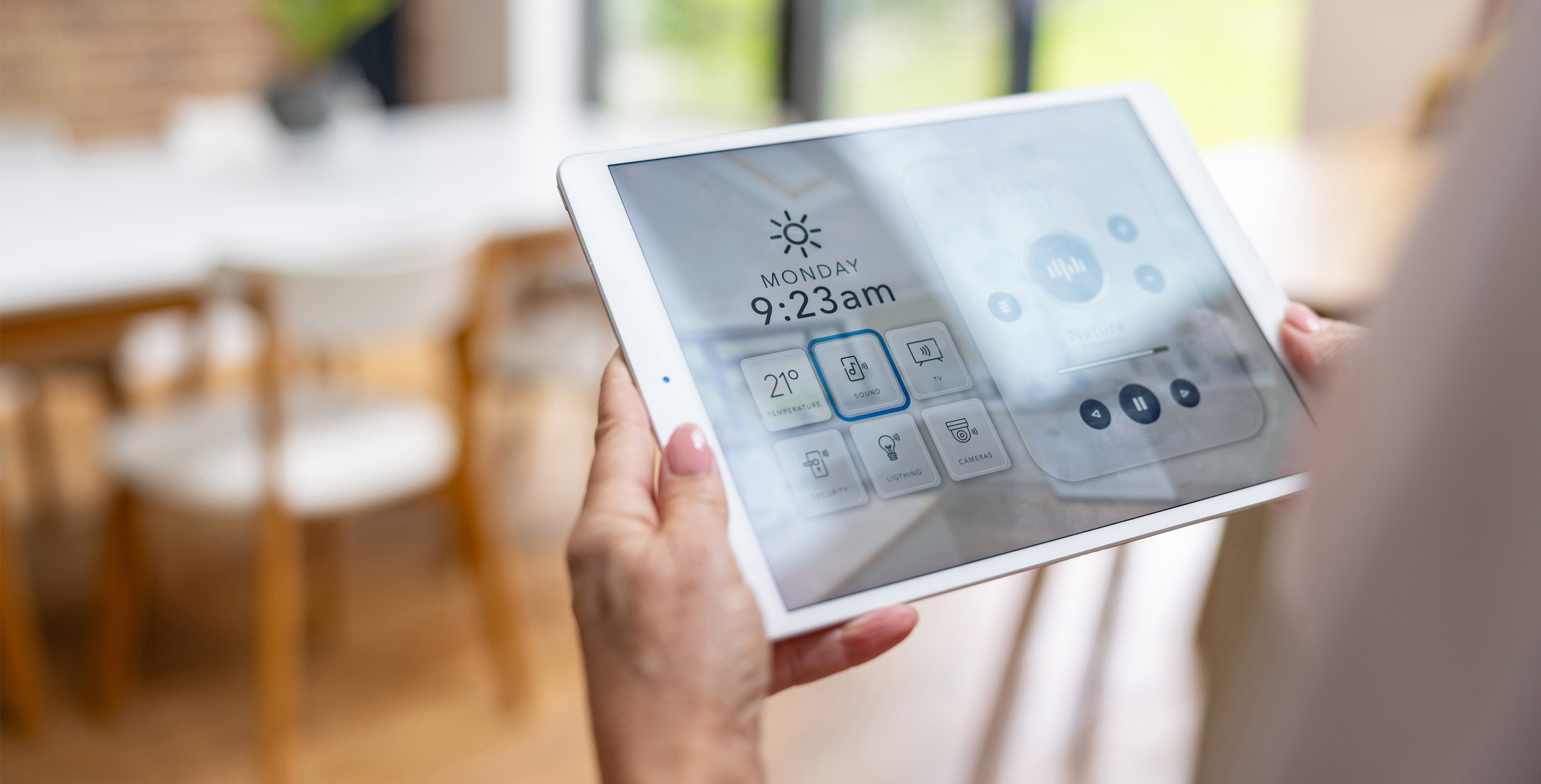 Eine Person steuert per Tablet das Smart Home, das an schnelle Glasfaser angebunden ist. Auf dem Display sind Symbole für Temperatur, Sicherheit und Beleuchtung zu sehen.